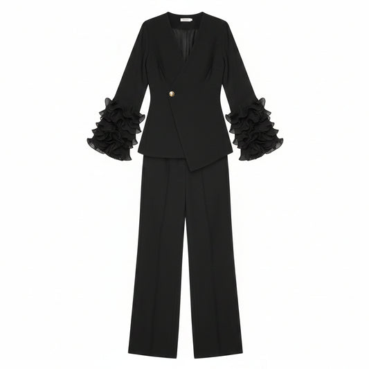 Person wearing a black outfit with ruffled sleeves in a room with a plant and mirror.