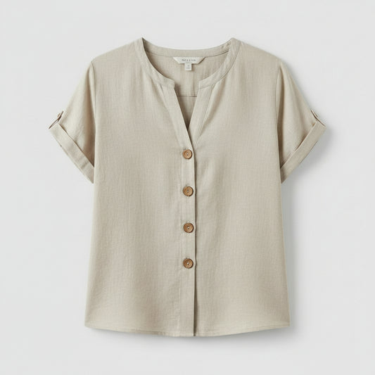 Woman wearing a light-colored button-up shirt with a neutral background